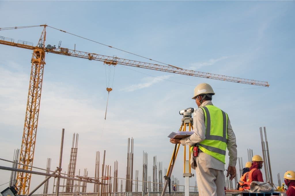 Site surveyor monitoring UAE construction project with tower crane